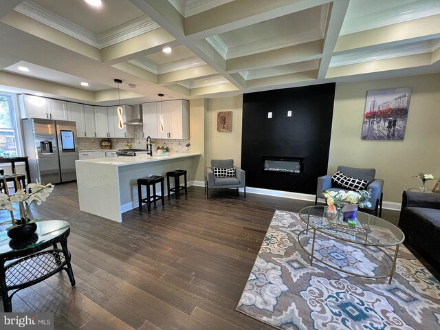 living room featuring coffered ceiling, a fireplace, dark hardwood / wood-style floors, and beam ceiling