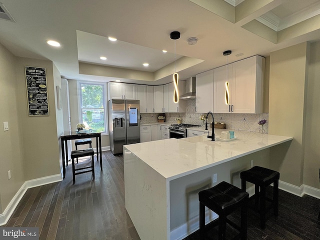 kitchen with white cabinetry, wall chimney exhaust hood, light stone countertops, appliances with stainless steel finishes, and dark wood-type flooring