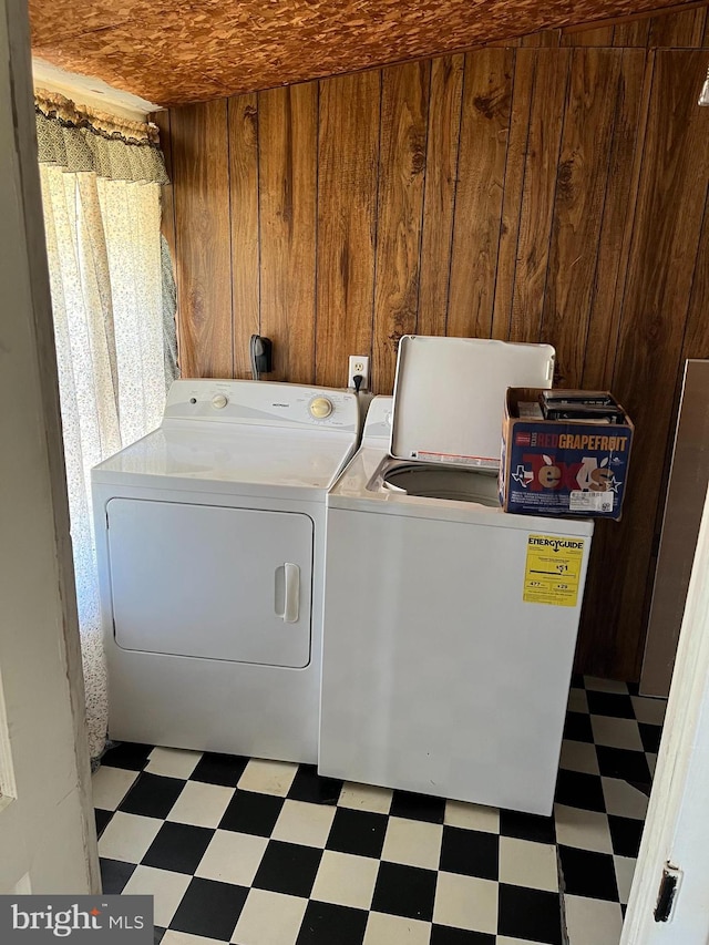 laundry area featuring wood walls and washer and dryer