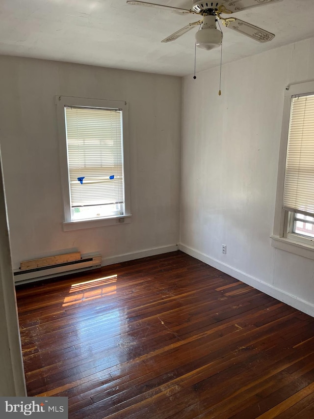 empty room with baseboard heating, dark wood-type flooring, ceiling fan, and plenty of natural light