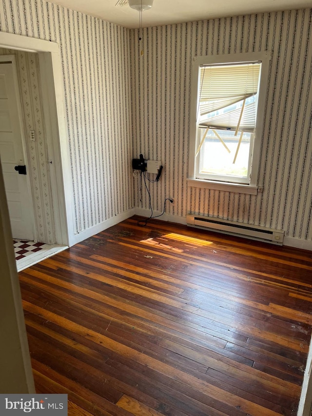 spare room featuring dark hardwood / wood-style flooring, baseboard heating, and ceiling fan