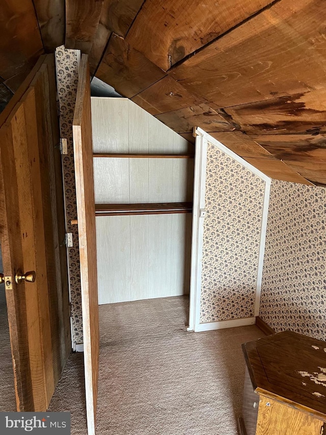 interior space featuring wooden ceiling, vaulted ceiling, and carpet