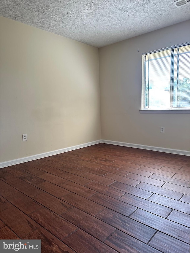 empty room with wood-type flooring and a textured ceiling