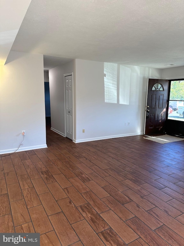 unfurnished living room with dark wood-type flooring and a textured ceiling