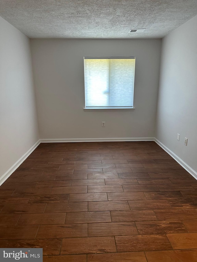 unfurnished room with a textured ceiling and dark hardwood / wood-style flooring