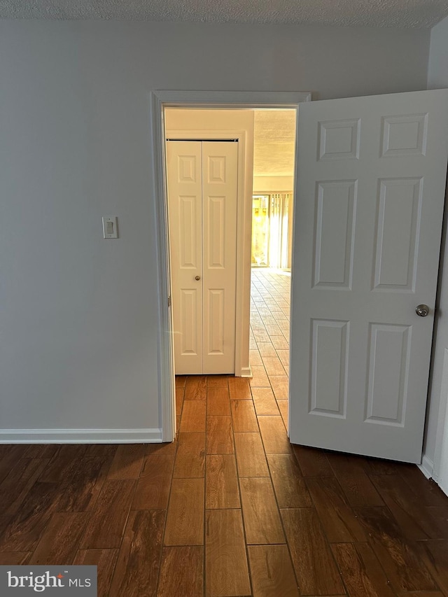 hall featuring a textured ceiling and dark hardwood / wood-style flooring