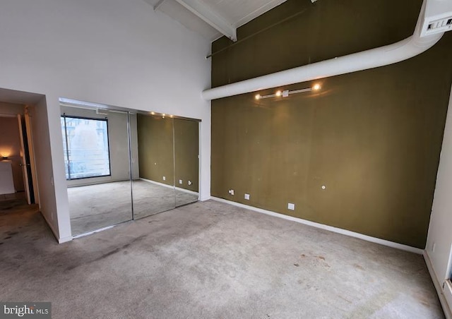 unfurnished bedroom featuring carpet floors, high vaulted ceiling, and beamed ceiling