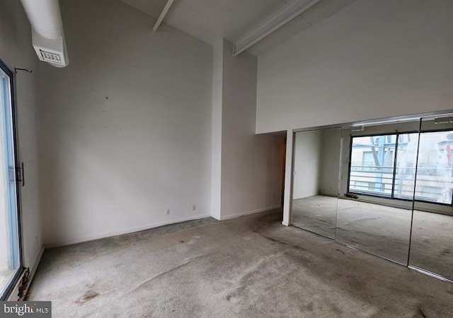 interior space featuring beamed ceiling, light colored carpet, high vaulted ceiling, and a closet