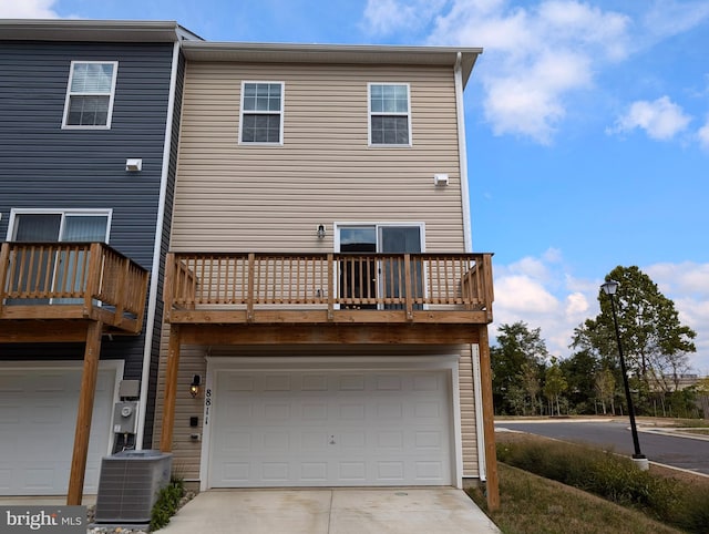 rear view of property featuring a balcony, a garage, and central AC unit