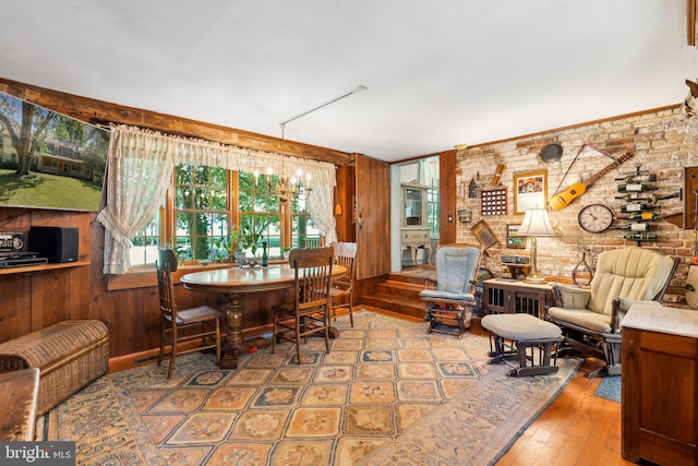 dining space with hardwood / wood-style flooring, brick wall, wooden walls, and a chandelier