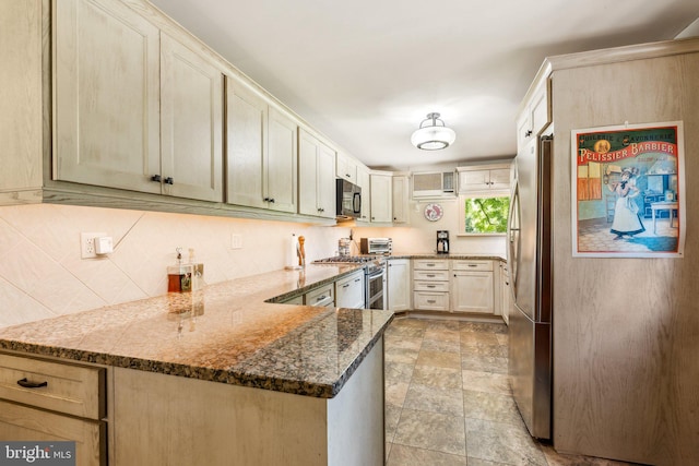 kitchen with stainless steel appliances, dark stone counters, and kitchen peninsula