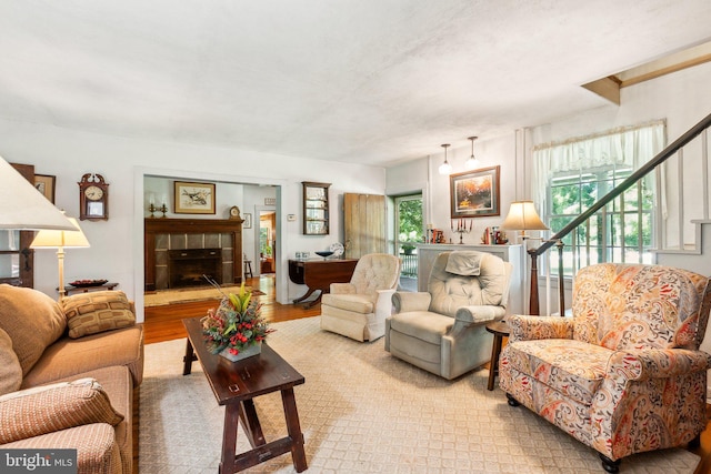 living room featuring a tiled fireplace and light wood-type flooring