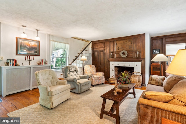 living room featuring hardwood / wood-style floors, a tile fireplace, and a textured ceiling