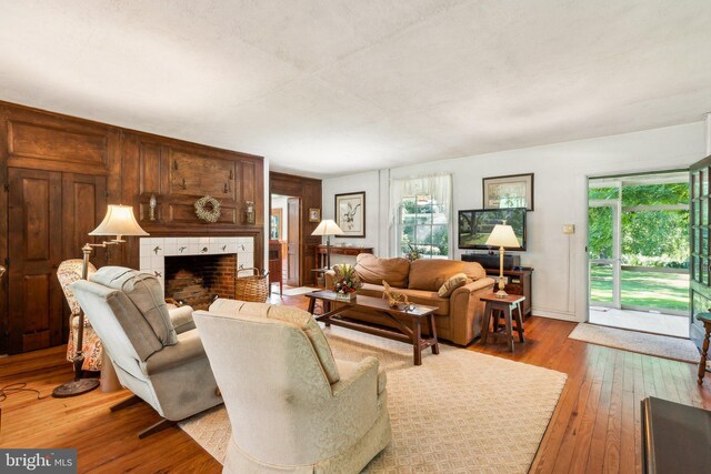 living room with a tiled fireplace and wood-type flooring