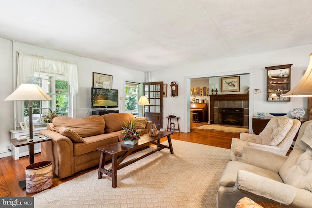 living room featuring hardwood / wood-style floors, radiator heating unit, and a tile fireplace