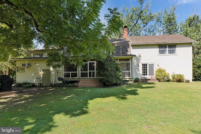 rear view of house featuring a wall unit AC, a sunroom, and a lawn