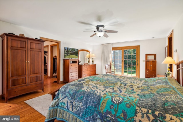 bedroom with ceiling fan, a walk in closet, hardwood / wood-style floors, and access to outside