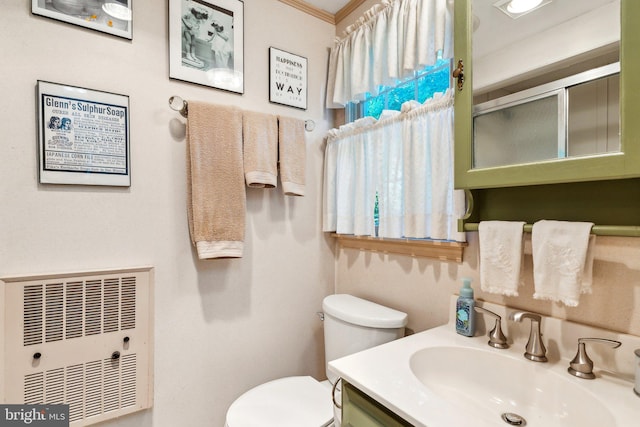 bathroom featuring crown molding, vanity, heating unit, a shower with shower door, and toilet