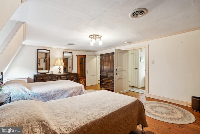 bedroom with ornamental molding and wood-type flooring