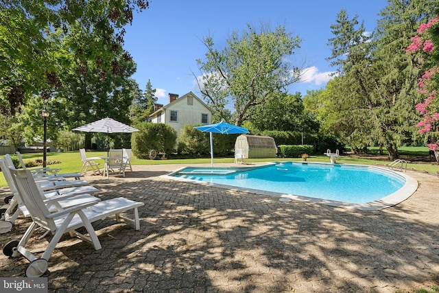 view of pool featuring a storage unit, a patio area, and a lawn