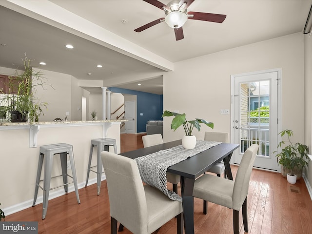 dining space featuring wood-type flooring, ceiling fan, and ornate columns