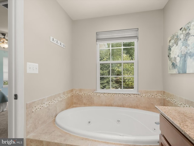 bathroom featuring tiled tub and vanity