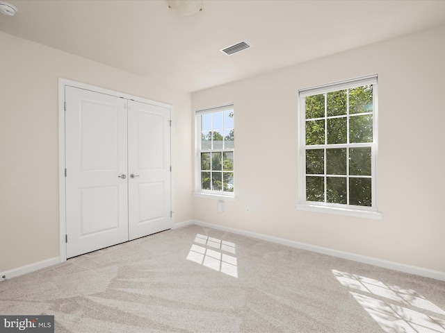 unfurnished bedroom with light carpet and a closet