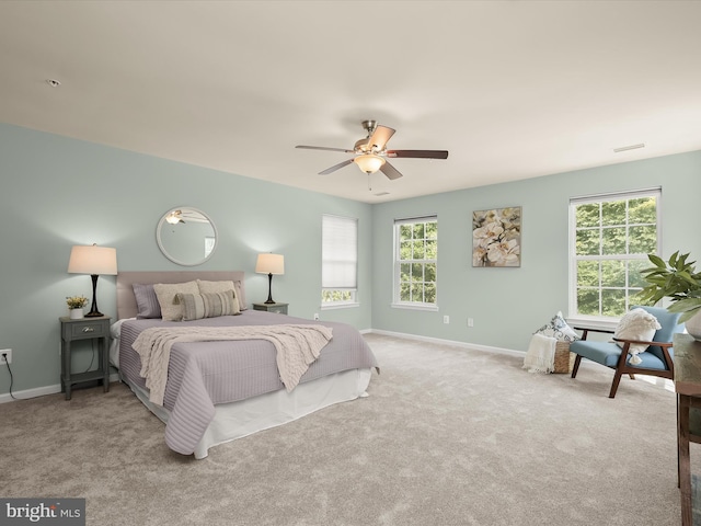 bedroom featuring multiple windows, light carpet, and ceiling fan