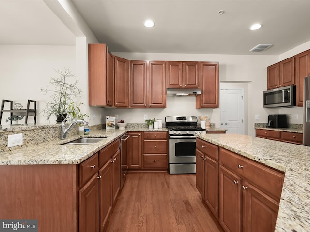 kitchen featuring light stone counters, stainless steel appliances, sink, and light wood-type flooring