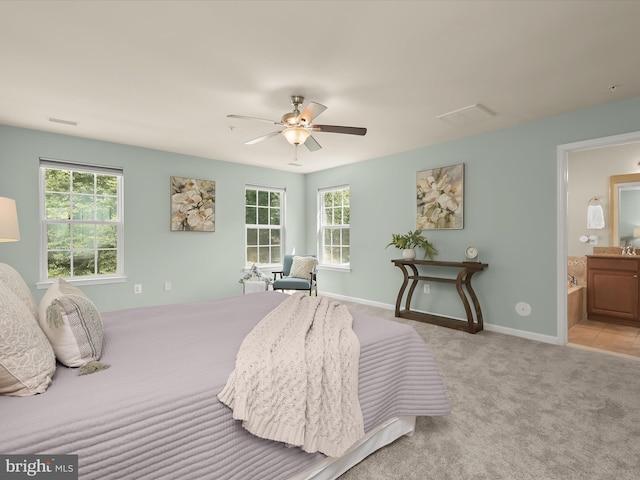 bedroom featuring multiple windows, ensuite bathroom, light carpet, and ceiling fan