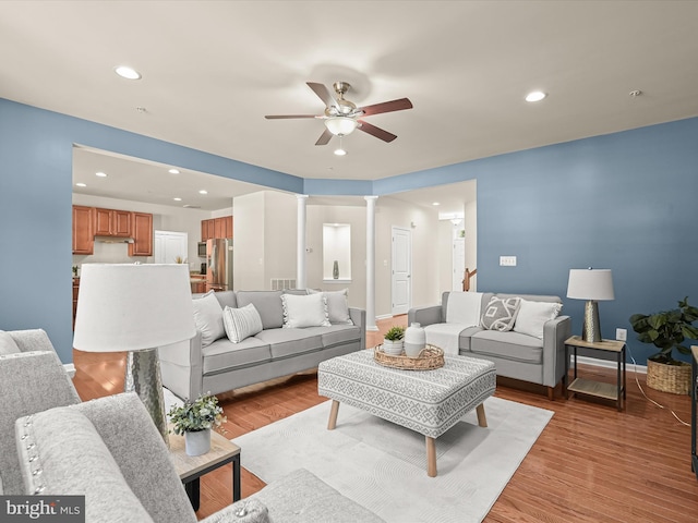 living room featuring ornate columns, ceiling fan, and light hardwood / wood-style flooring