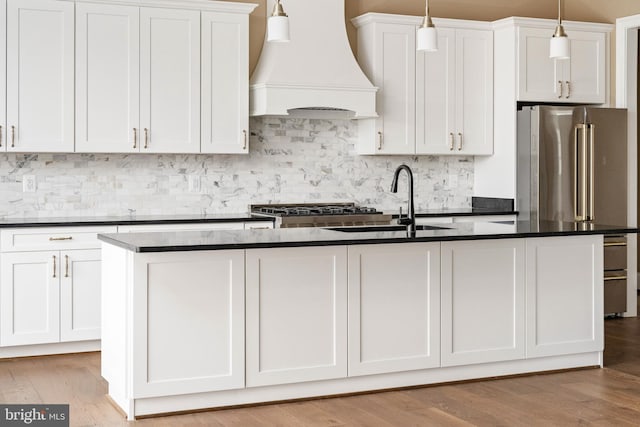 kitchen featuring a center island with sink, custom exhaust hood, white cabinets, and sink