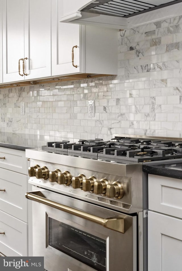 kitchen featuring stainless steel range, tasteful backsplash, white cabinets, and extractor fan