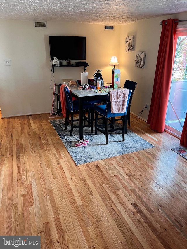 dining room with light hardwood / wood-style floors and a textured ceiling