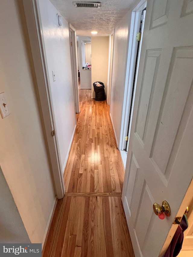 corridor featuring light hardwood / wood-style floors and a textured ceiling