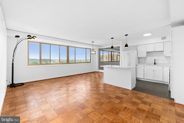 kitchen with white cabinetry, sink, white refrigerator, hanging light fixtures, and a center island