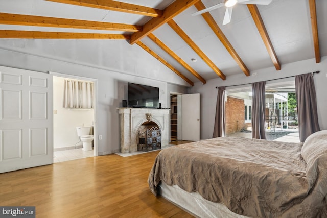 bedroom featuring vaulted ceiling with beams, ensuite bathroom, light wood-style flooring, a fireplace, and access to exterior