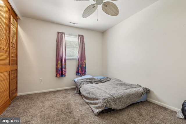 carpeted bedroom with ceiling fan, a closet, and baseboards