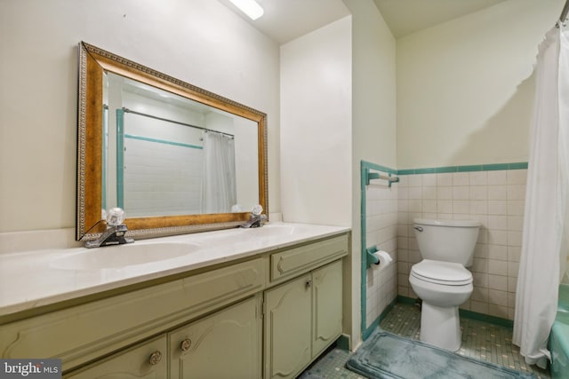 bathroom with tile walls, double vanity, toilet, a sink, and tile patterned floors