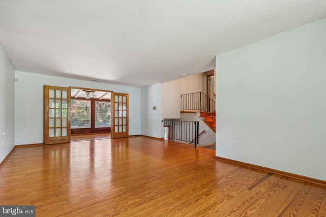 unfurnished living room with light wood-style floors, stairs, and baseboards