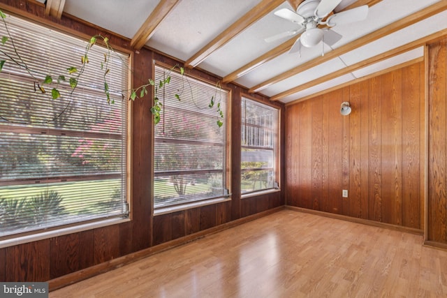 empty room with light wood-type flooring, ceiling fan, wooden walls, and beam ceiling