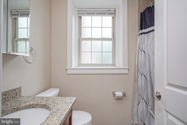 bathroom featuring toilet, vanity, and a wealth of natural light