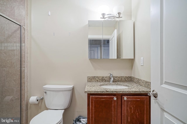 bathroom with a shower with shower door, vanity, and toilet