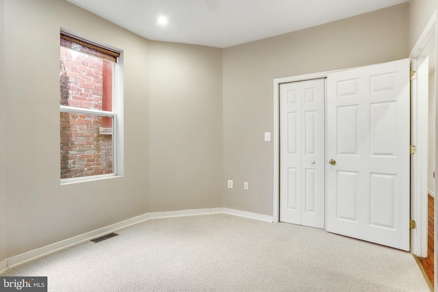 unfurnished bedroom with light carpet and a closet