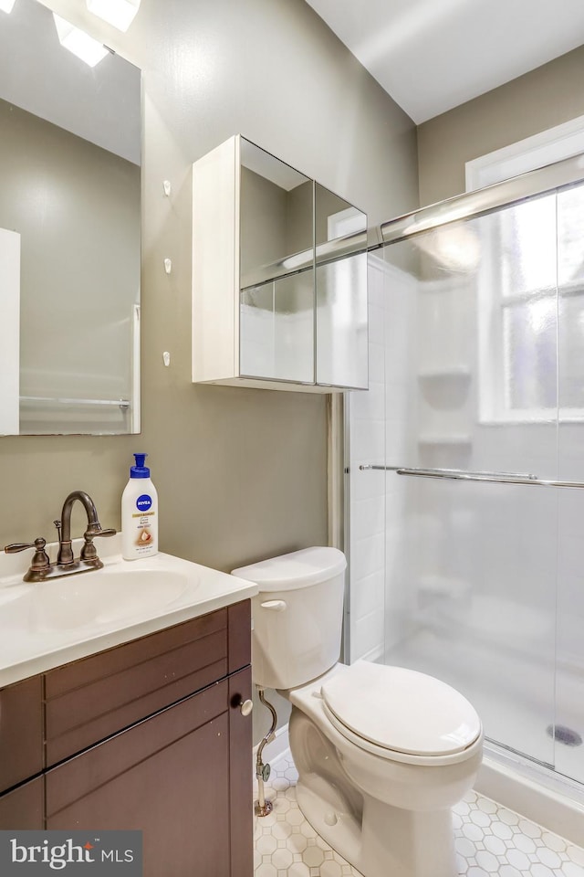 bathroom featuring a shower with shower door, tile patterned floors, toilet, and vanity