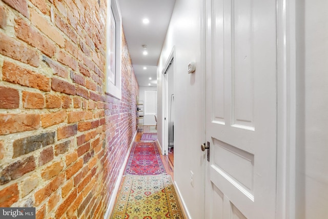 corridor featuring hardwood / wood-style floors and brick wall