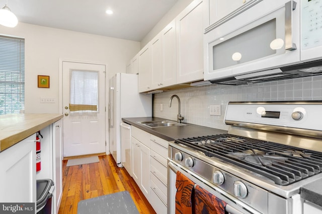 kitchen featuring white appliances, sink, decorative backsplash, light wood-type flooring, and white cabinetry