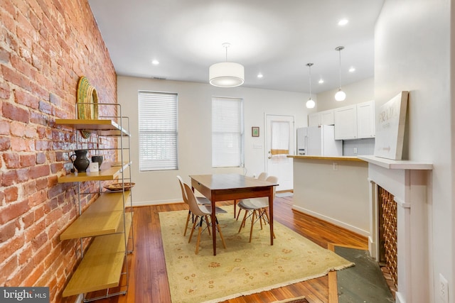 dining space featuring brick wall and dark hardwood / wood-style floors