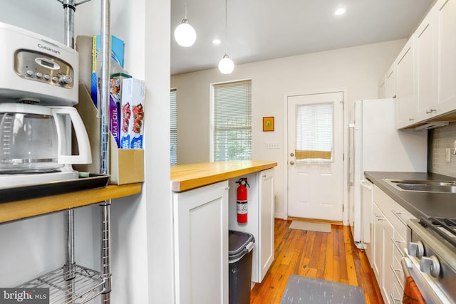 kitchen with decorative backsplash, white cabinets, washer / dryer, stove, and light hardwood / wood-style flooring