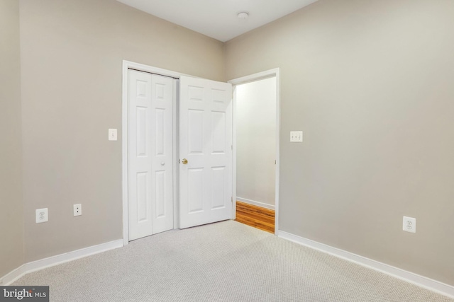 unfurnished bedroom featuring light carpet and a closet